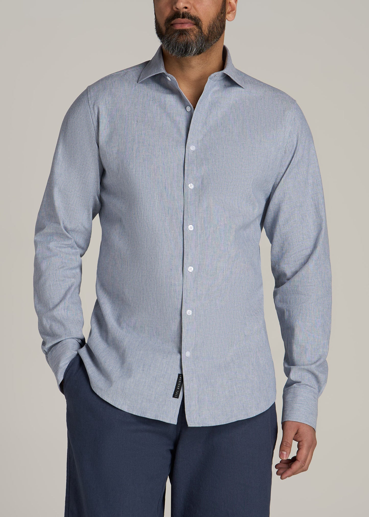 A tall man wearing American Tall's Stretch Linen Dress Shirt for Tall Men in Blue and White Pinstripe