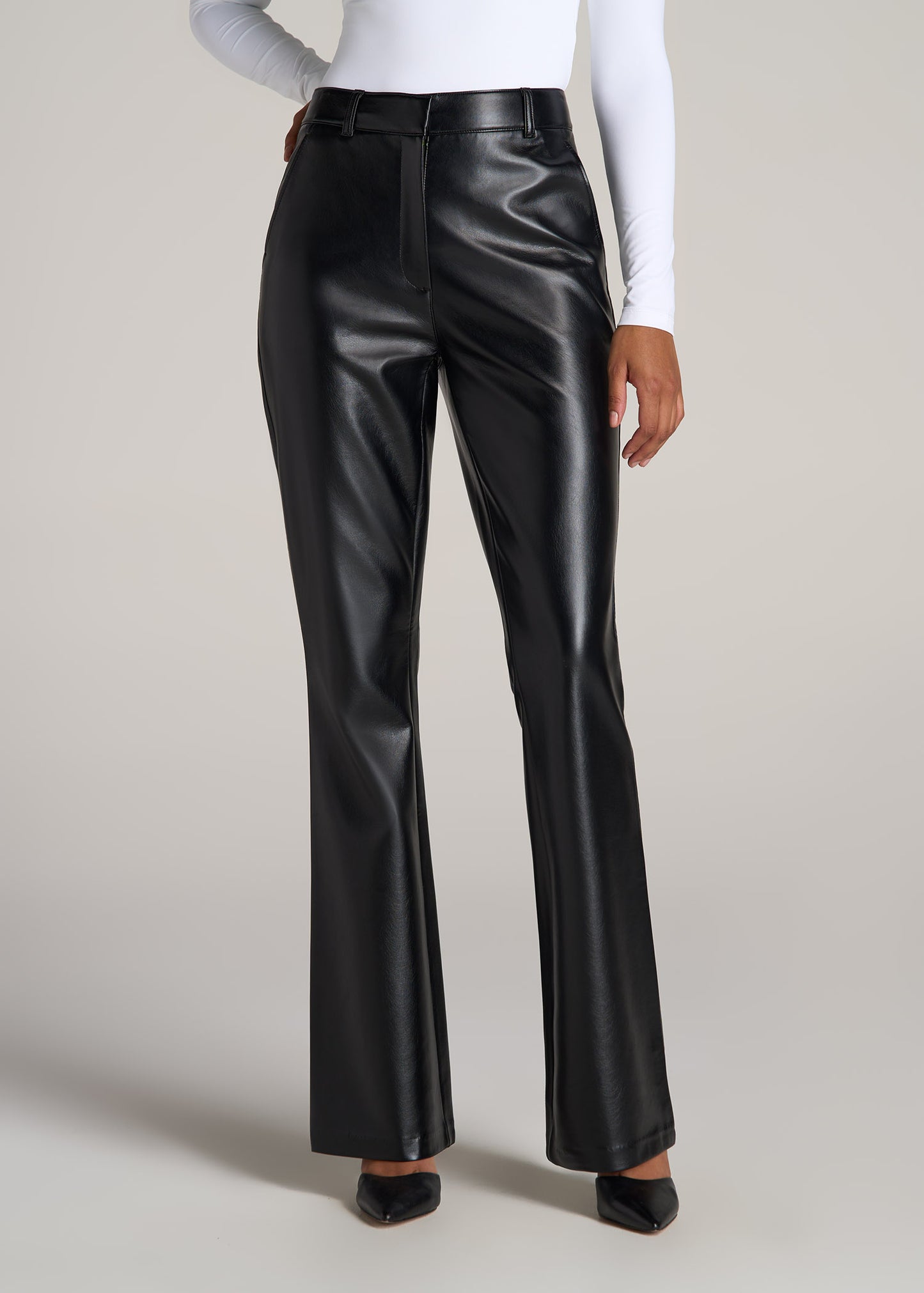 A tall woman wearing American Tall's Faux Leather Pants in the color black.