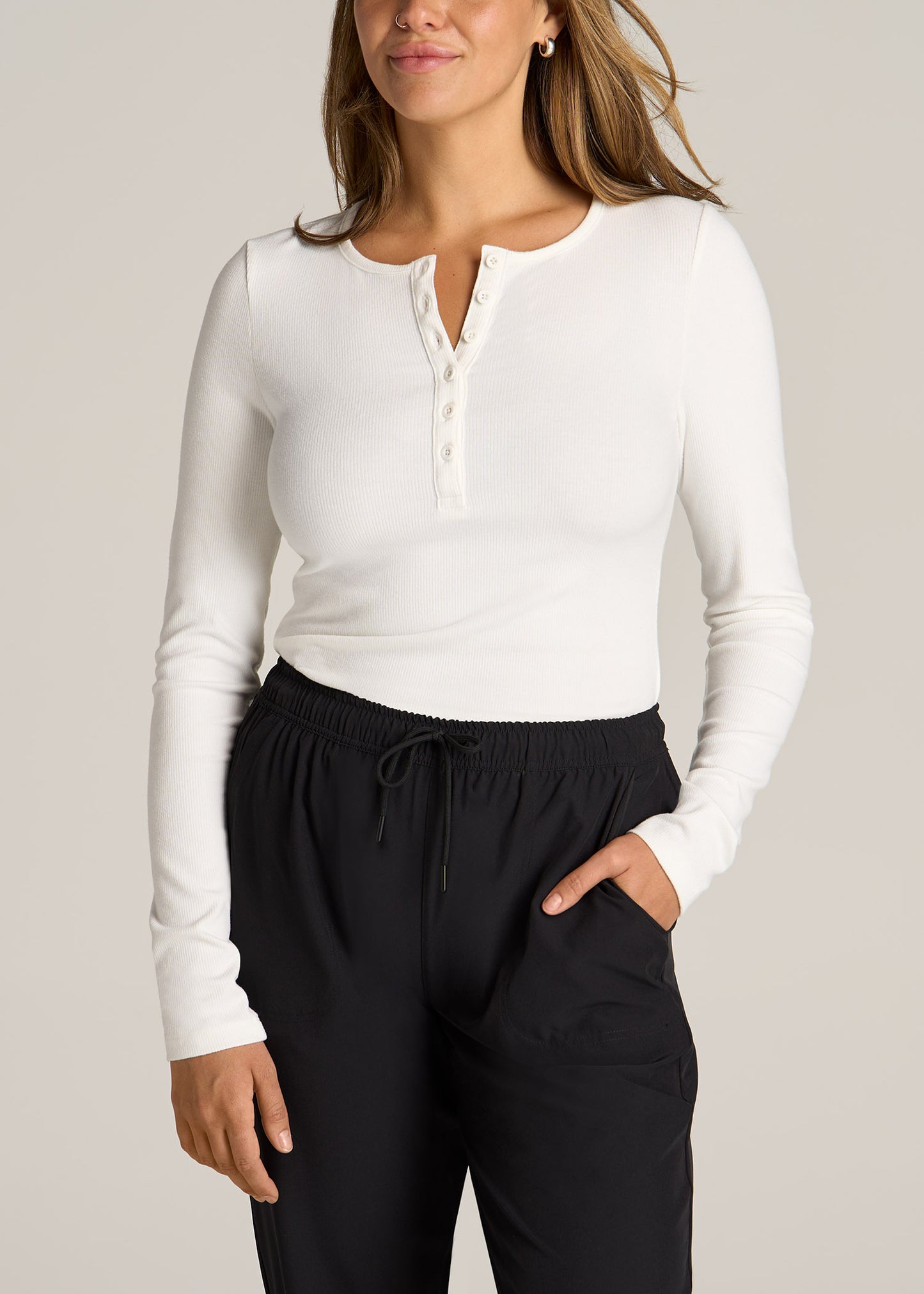 A tall woman wearing American Tall's Long Sleeve Ribbed Crewneck Women's Tall Henley Shirt in the color cream.