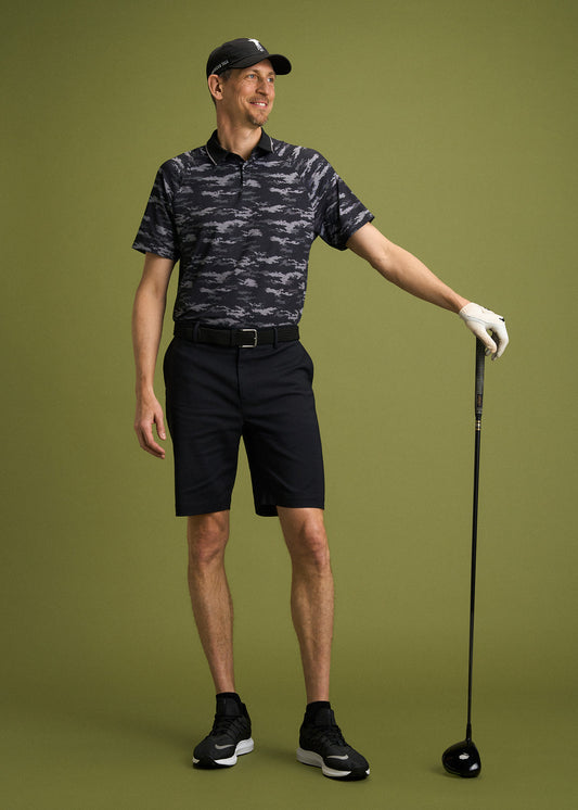 A tall man wearing a golf polo, shorts and a hat from American Tall