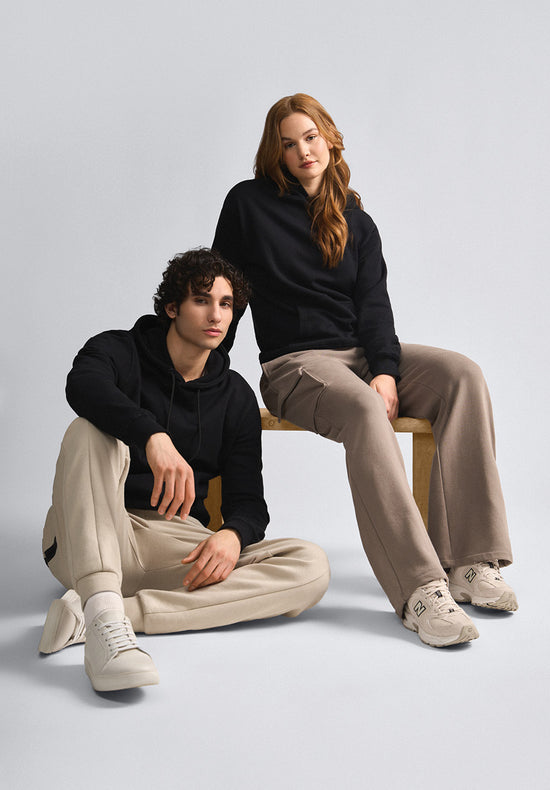 A tall man wearing a pullover, a pair of joggers and sneakers from American Tall