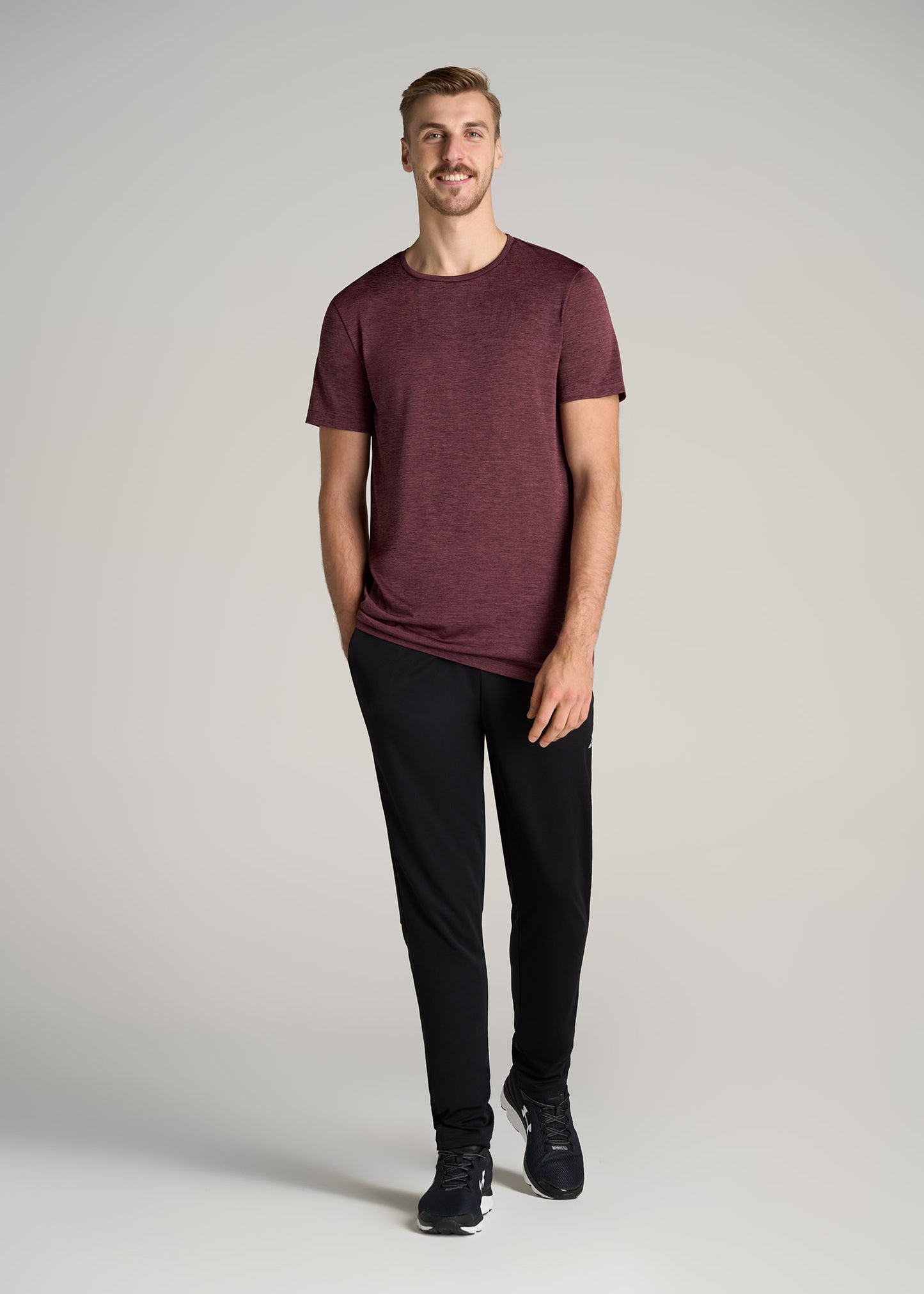 A tall man wearing American Tall's A.T. Performance MODERN-FIT Athletic Jersey Tall Tee in Rust Red.