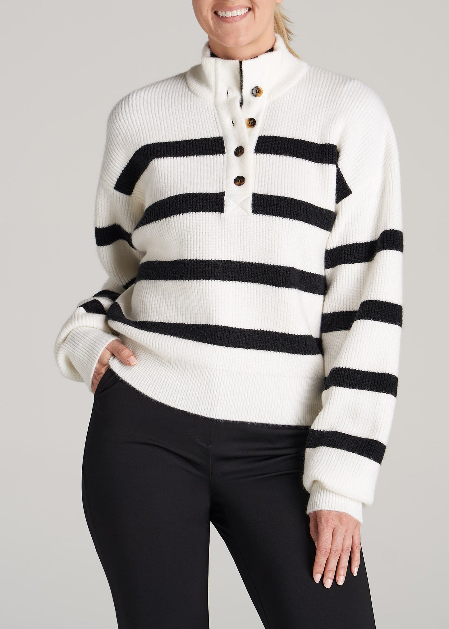 A tall woman wearing American Tall's Button Front Mock Neck Sweater in Off White & Black Stripe.