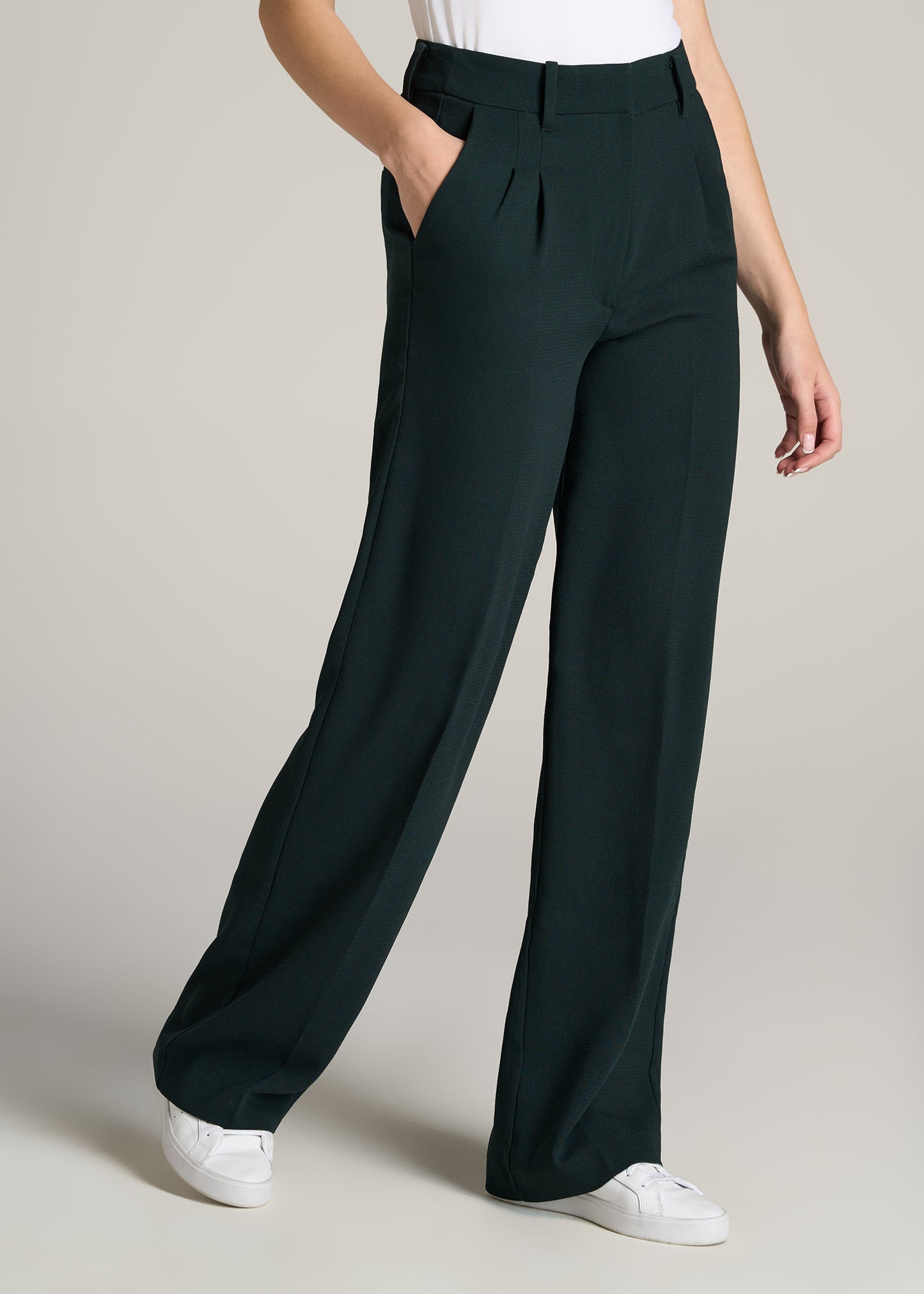 A tall woman wearing American Tall's Pleated Wide Leg Dress Pants in the color Midnight Green.