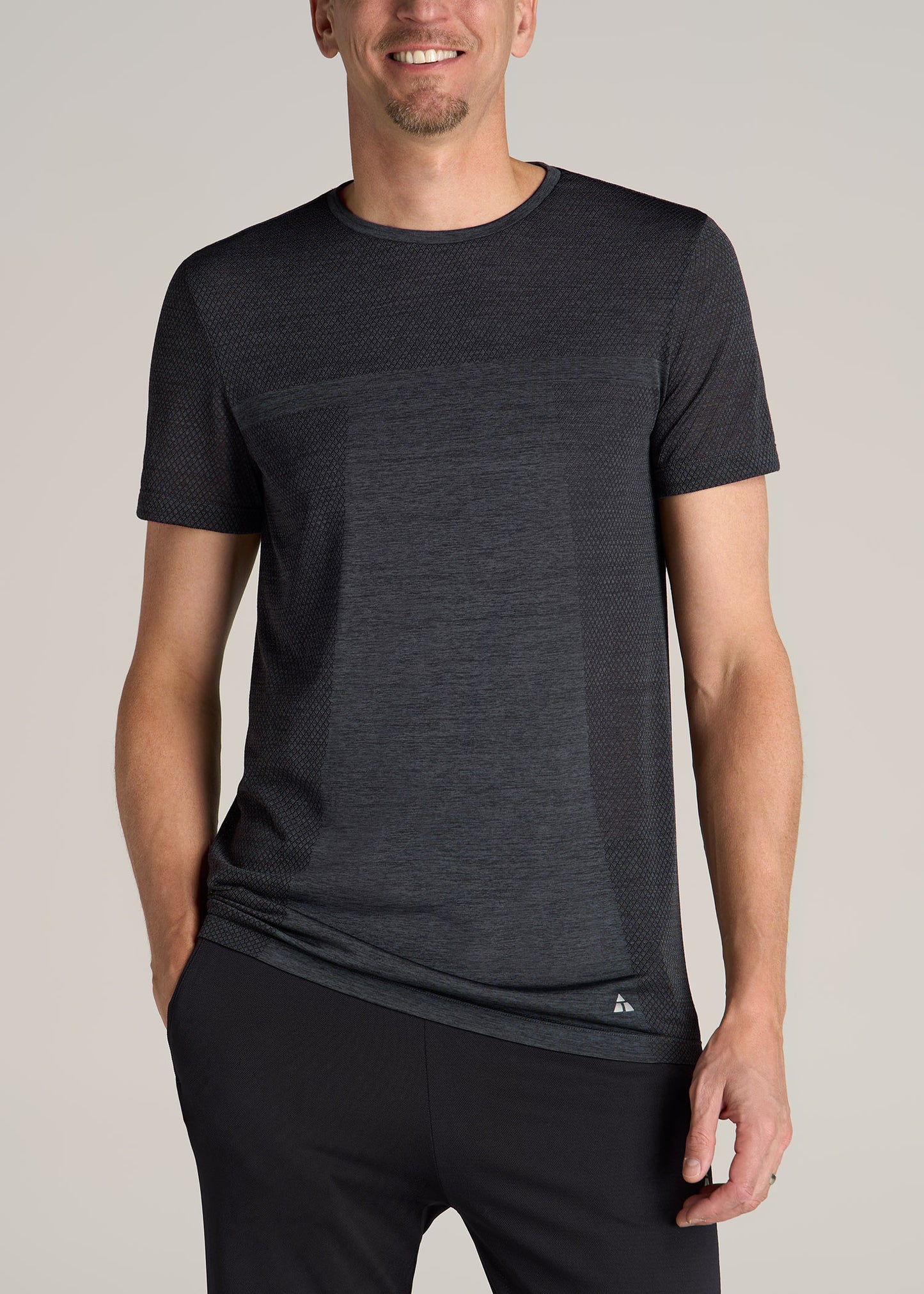 A tall man wearing American Tall's A.T. Performance MODERN-FIT Engineered Athletic Tall Tee in Charcoal Mix.