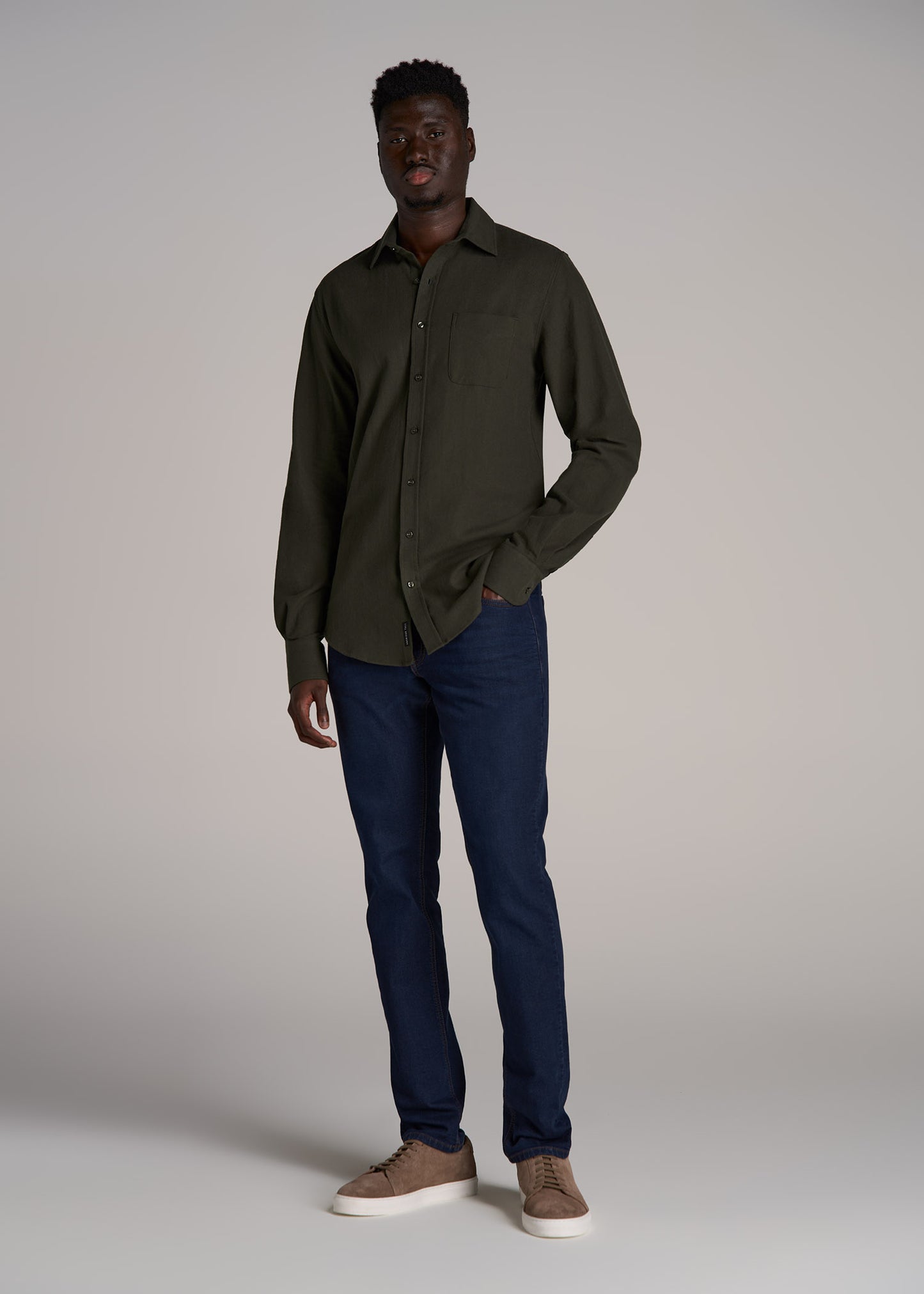 A tall man wearing American Tall's Mason Semi-Relaxed Jeans for Tall Men in Blue Steel with a Nelson Flannel Shirt for Tall Men in Hunter Green.