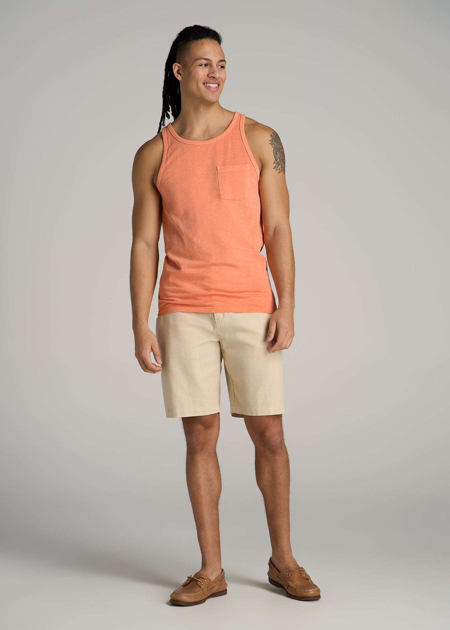 A tall man wearing American Tall's Slub Pocket Tank Top in Apricot Crush and Linen Shorts in Sandstone.