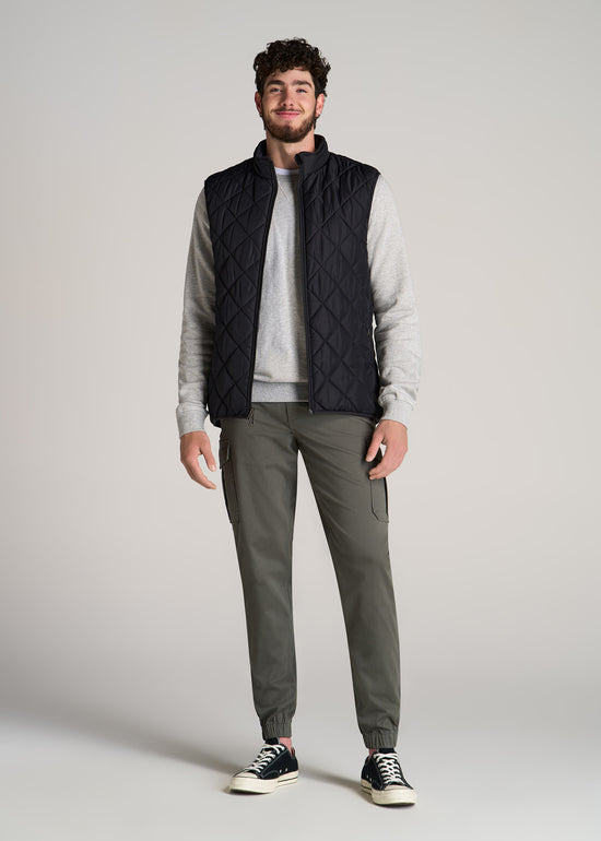 A tall man wearing American Tall's Quilted Reversible Vest in the color Black.