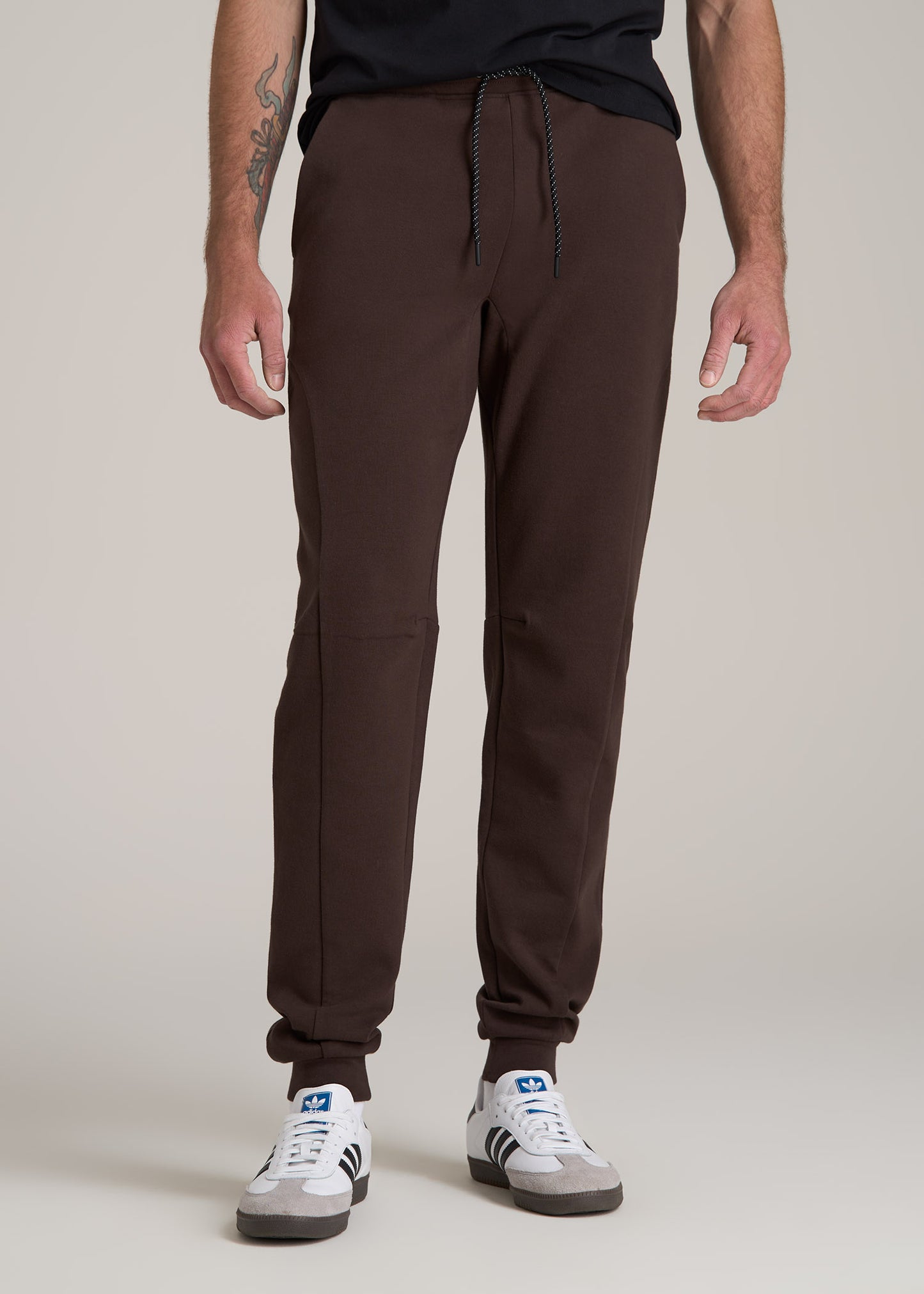 A tall man wearing American Tall's Tall Men's Utility Fleece Joggers in Espresso