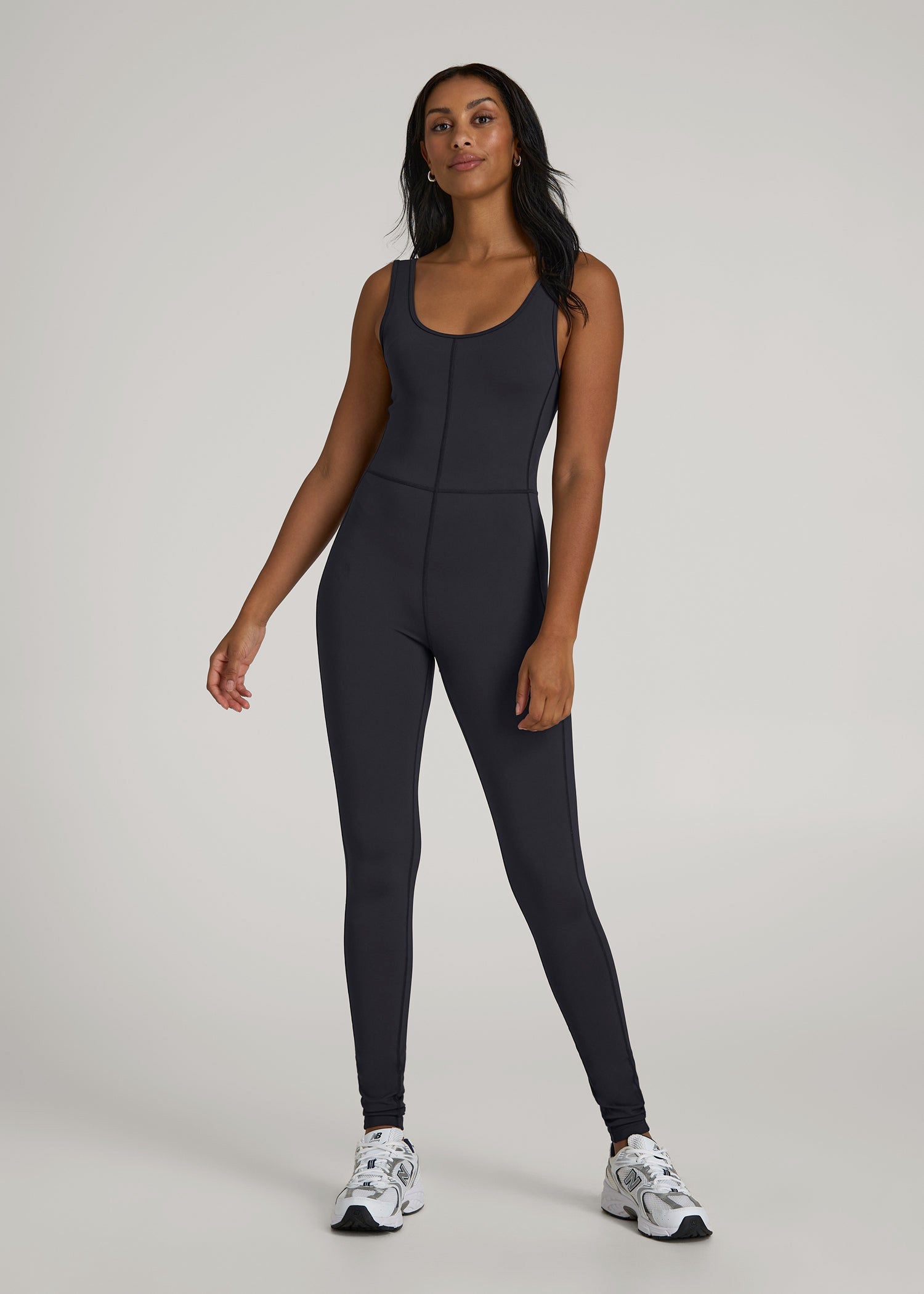 Tall woman wearing the American Tall Balance Scoop Neck Jumpsuit in Black, a fitted athleisure jumpsuit for active days