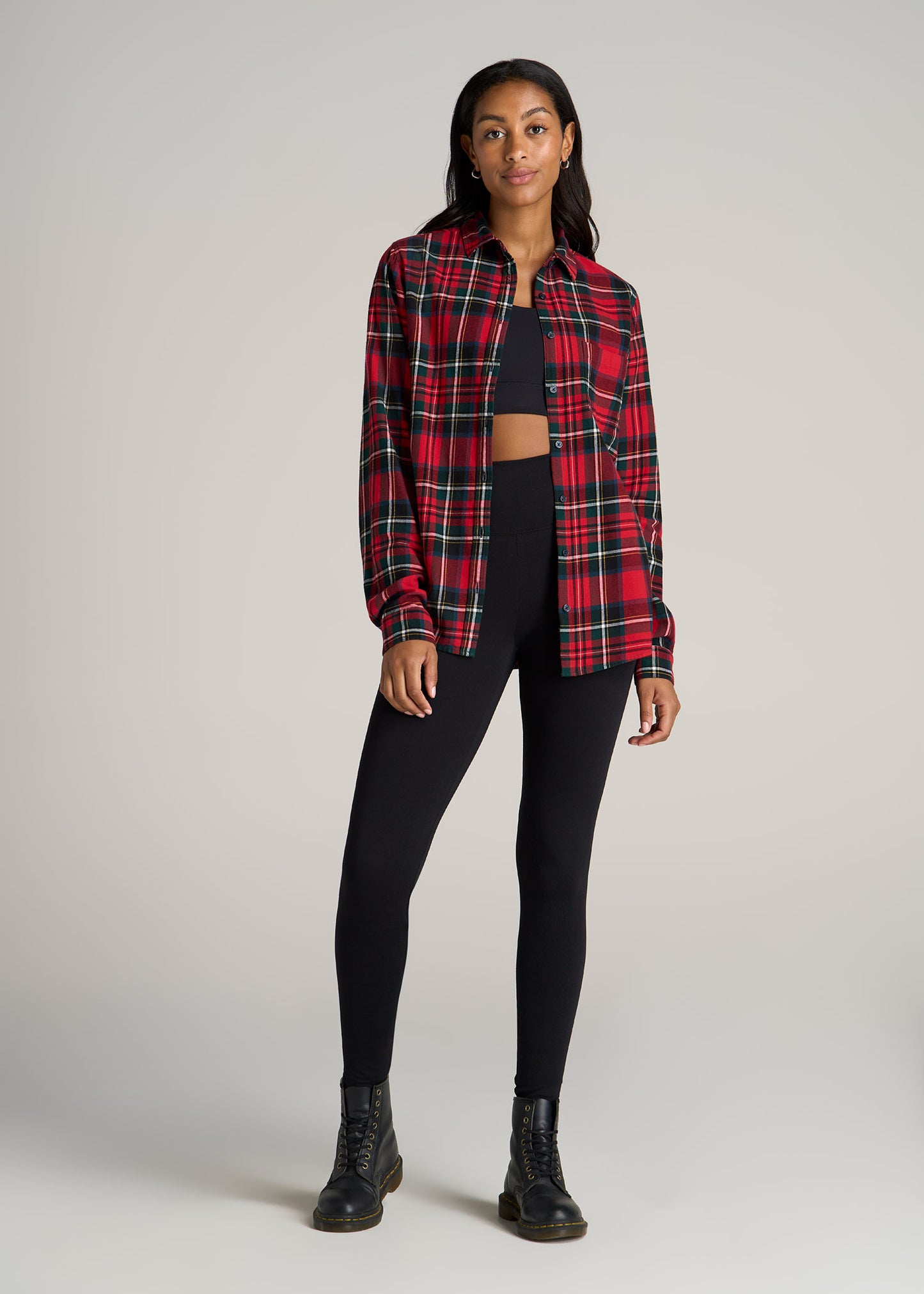 A tall woman wearing American Tall's flannel button-up shirt in red and green tartan.