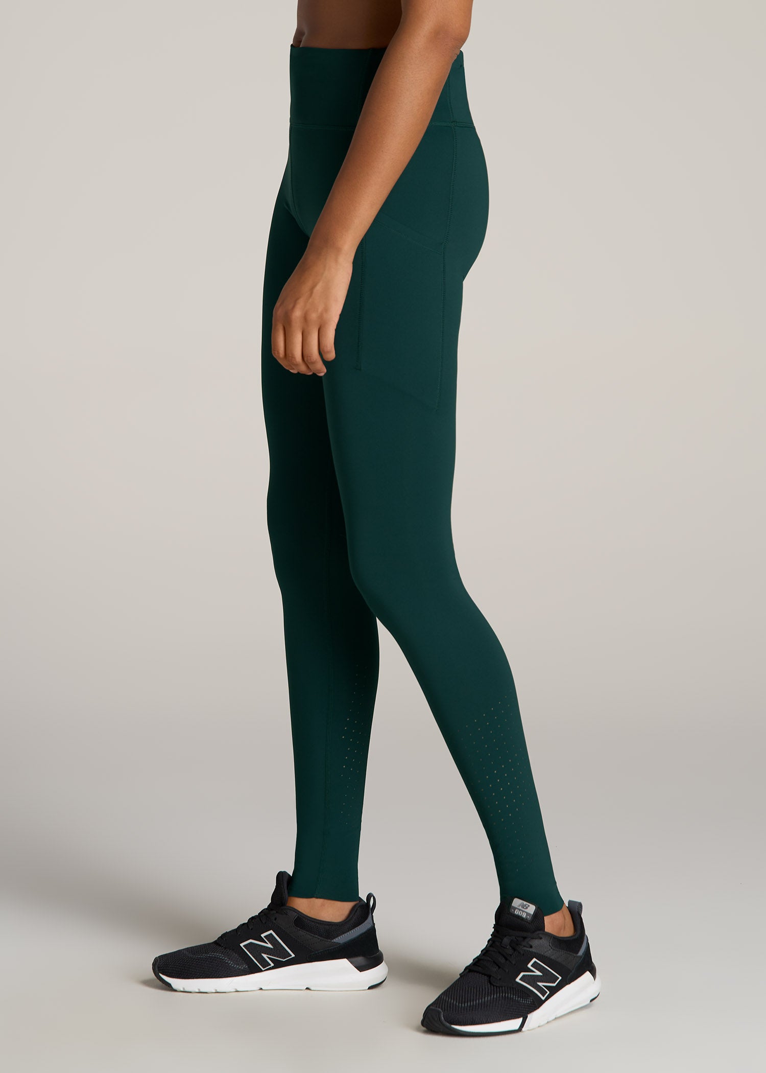 A tall woman wearing American Tall's Mid-Rise Run Legging in emerald.g