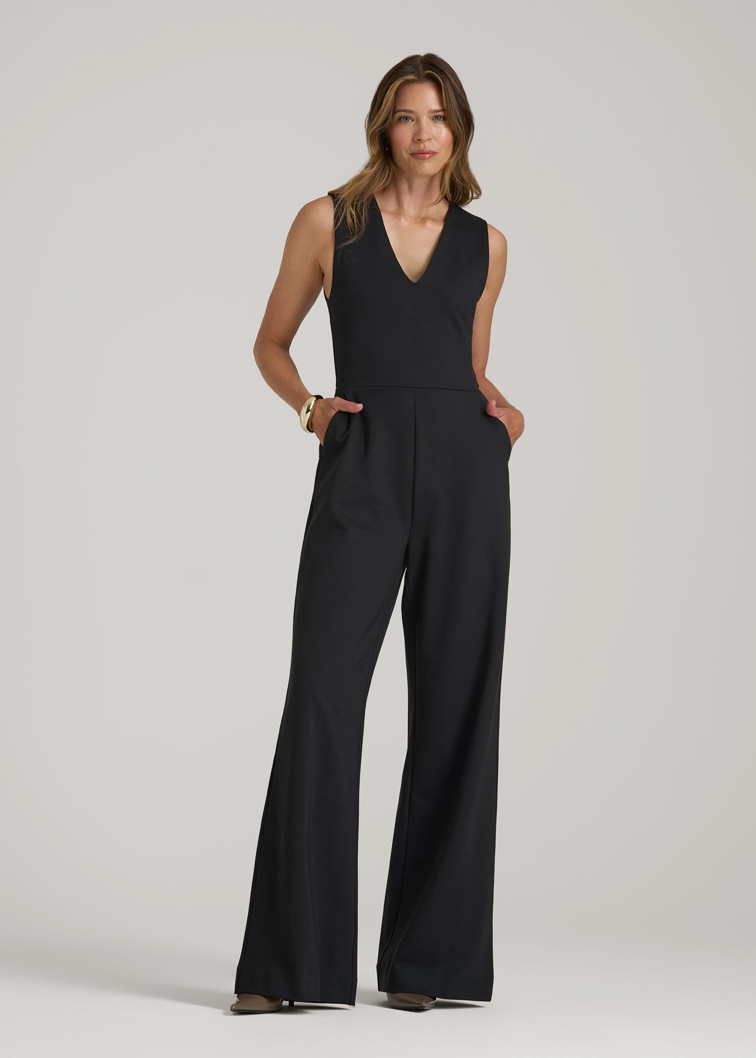 Tall woman wearing the American Tall Flex Ponte Wide-Leg V-Neck Jumpsuit in Black, styled for work and dinner occasions
