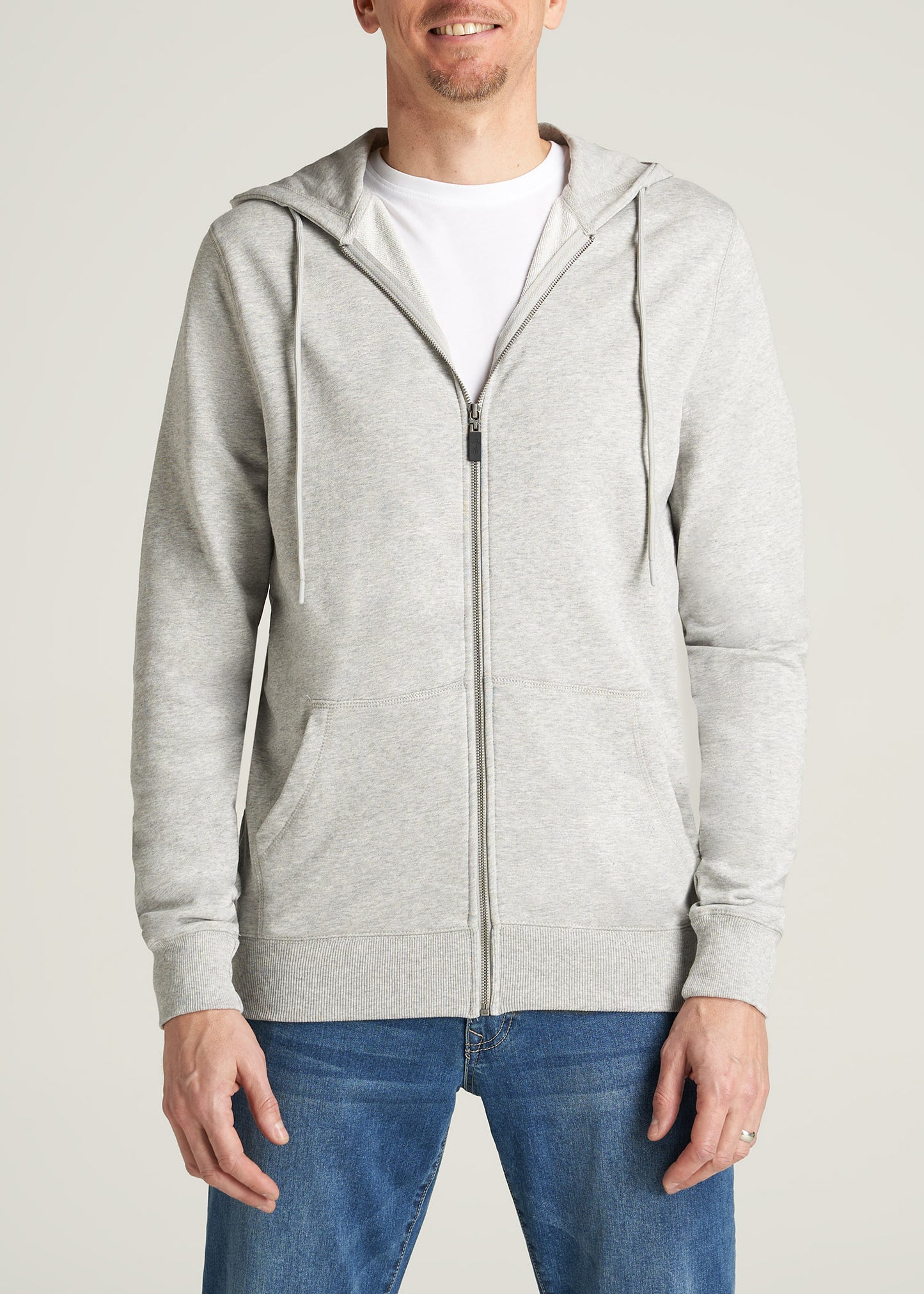 A tall man wearing a full-zip French terry hoodie in a light grey mix.