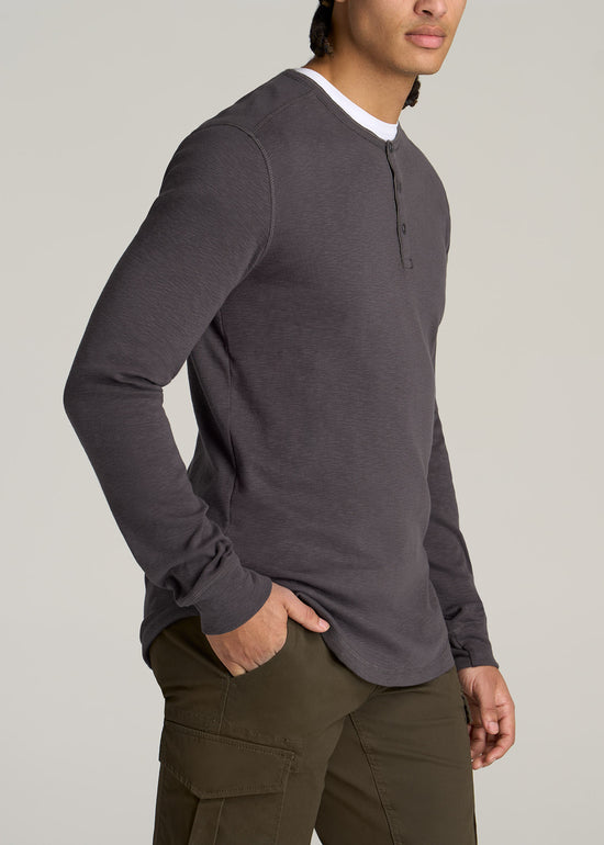 A tall man wearing American Tall's Heavy Slub Henley Shirt in the color Charcoal.
