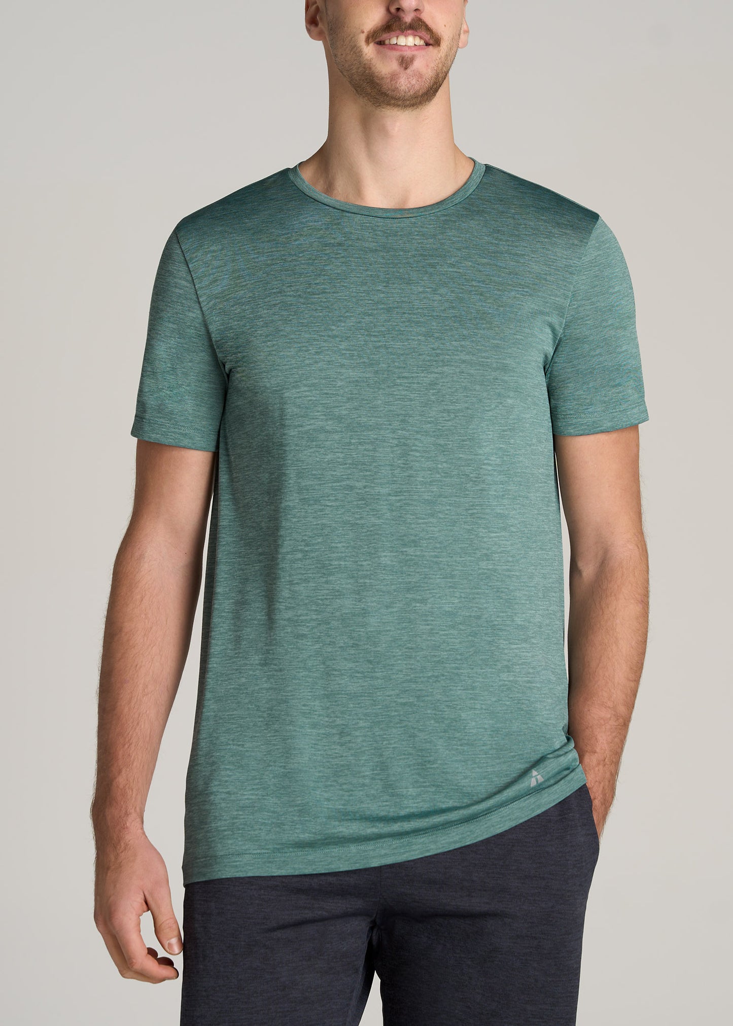 A tall man wearing American Tall's A.T. Performance MODERN-FIT Athletic Jersey Tall Tee in Green Mix.