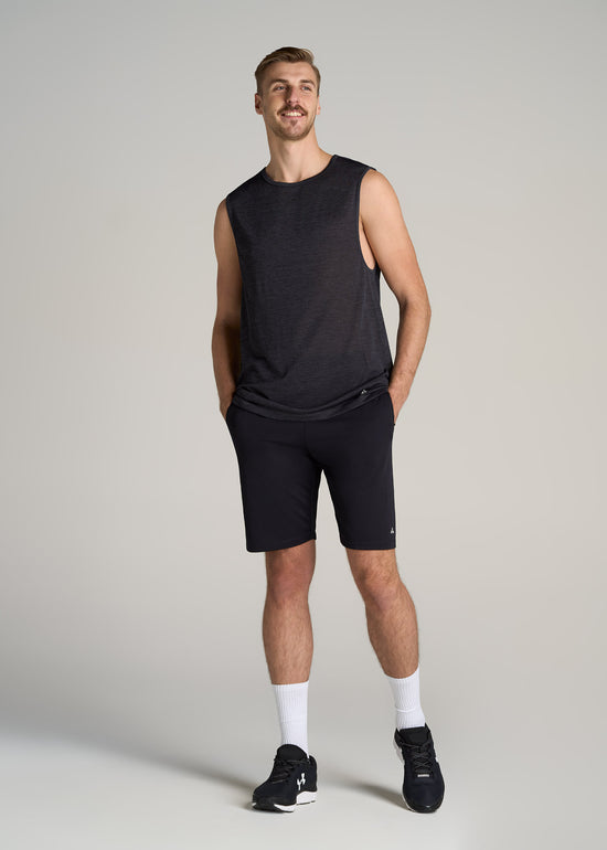 A tall man wearing American Tall's A.T. Performance Engineered Tank and Shorts in the color Black.