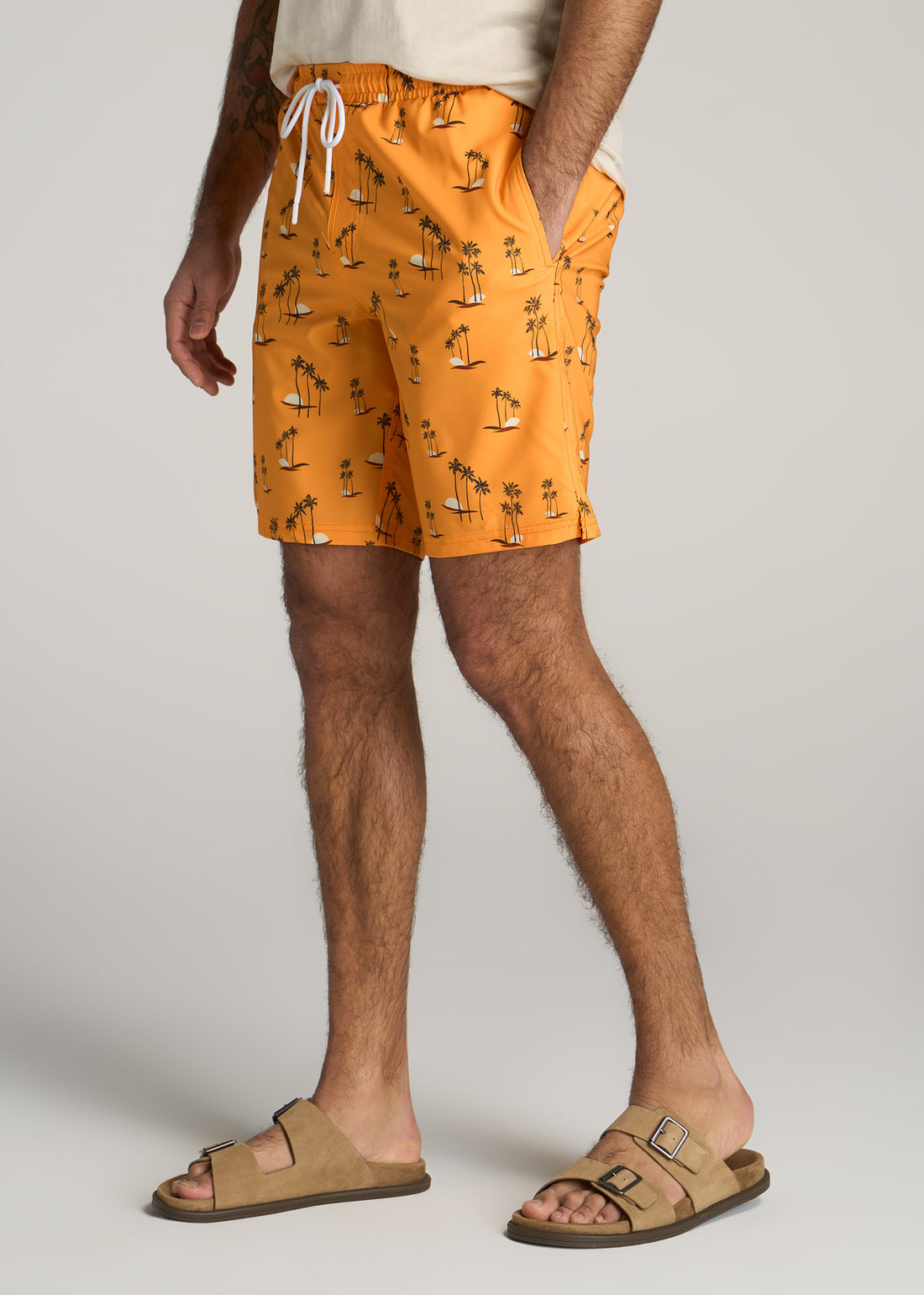 Tall man wearing orange swim shorts with an island pattern.