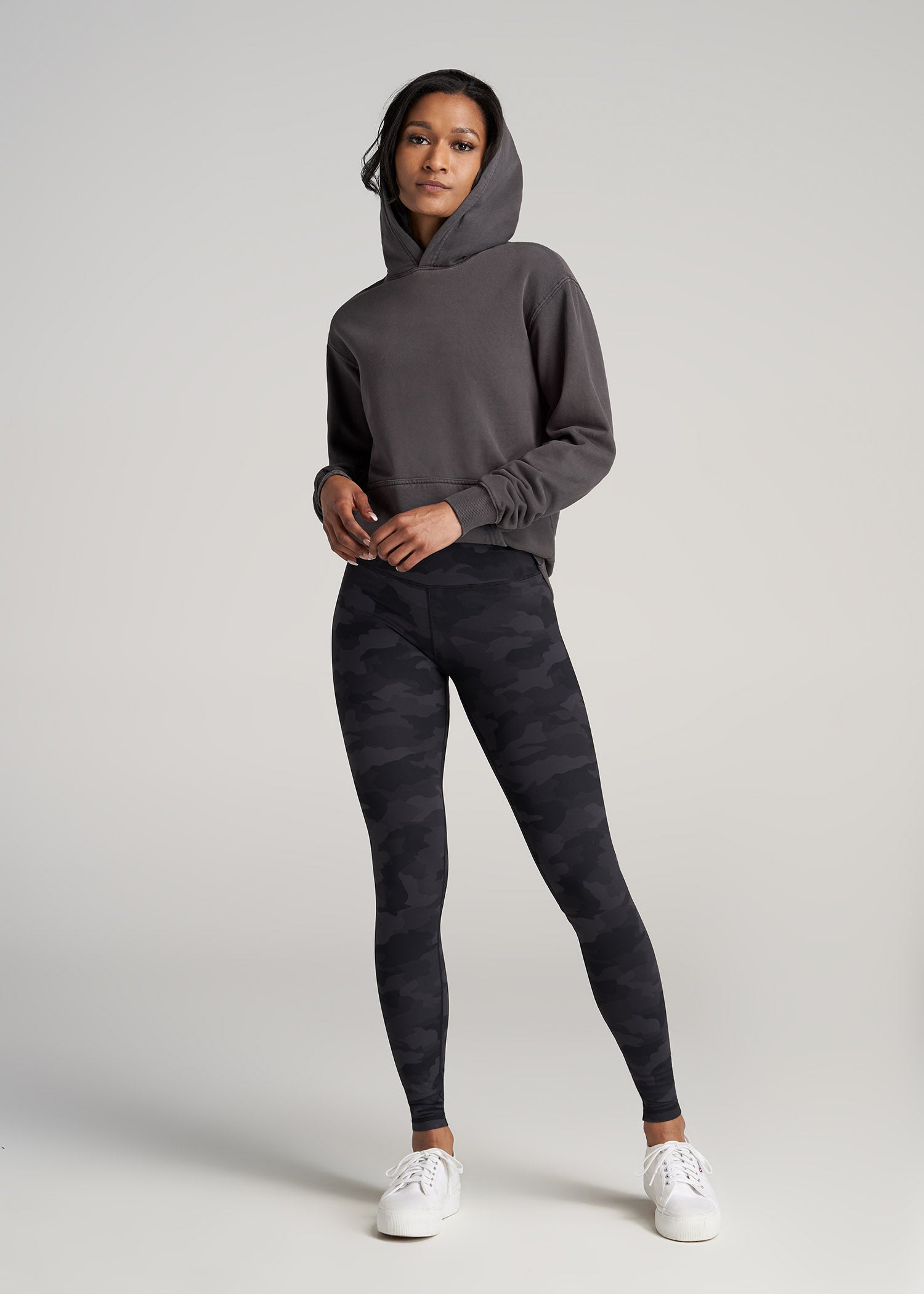A tall woman wearing American Tall's Balance High-Rise Leggings in the color Grey Camo.