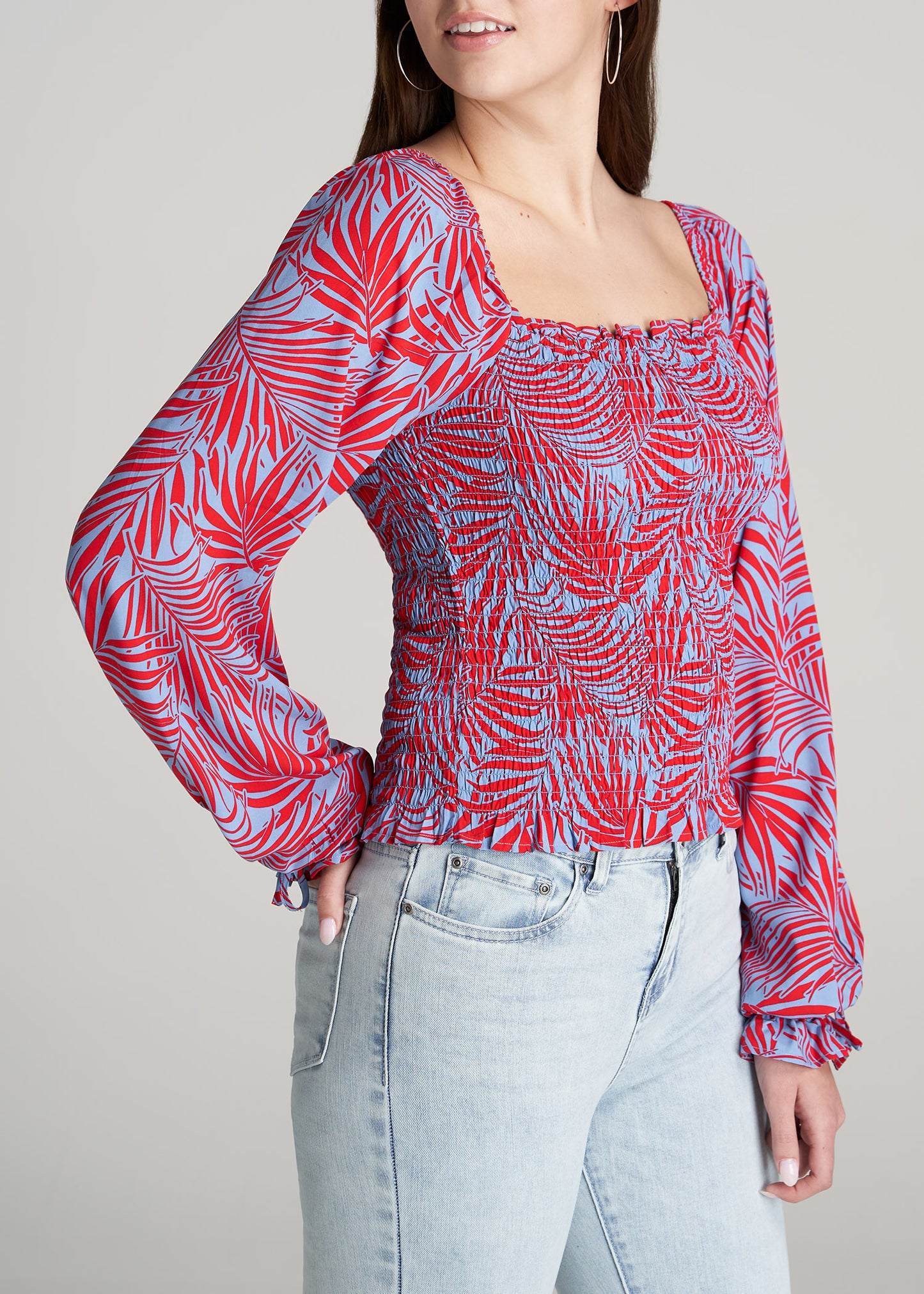 A tall woman wearing American Tall's Balloon Sleeve Smocked Blouse in Red and Blue Tropical print.
