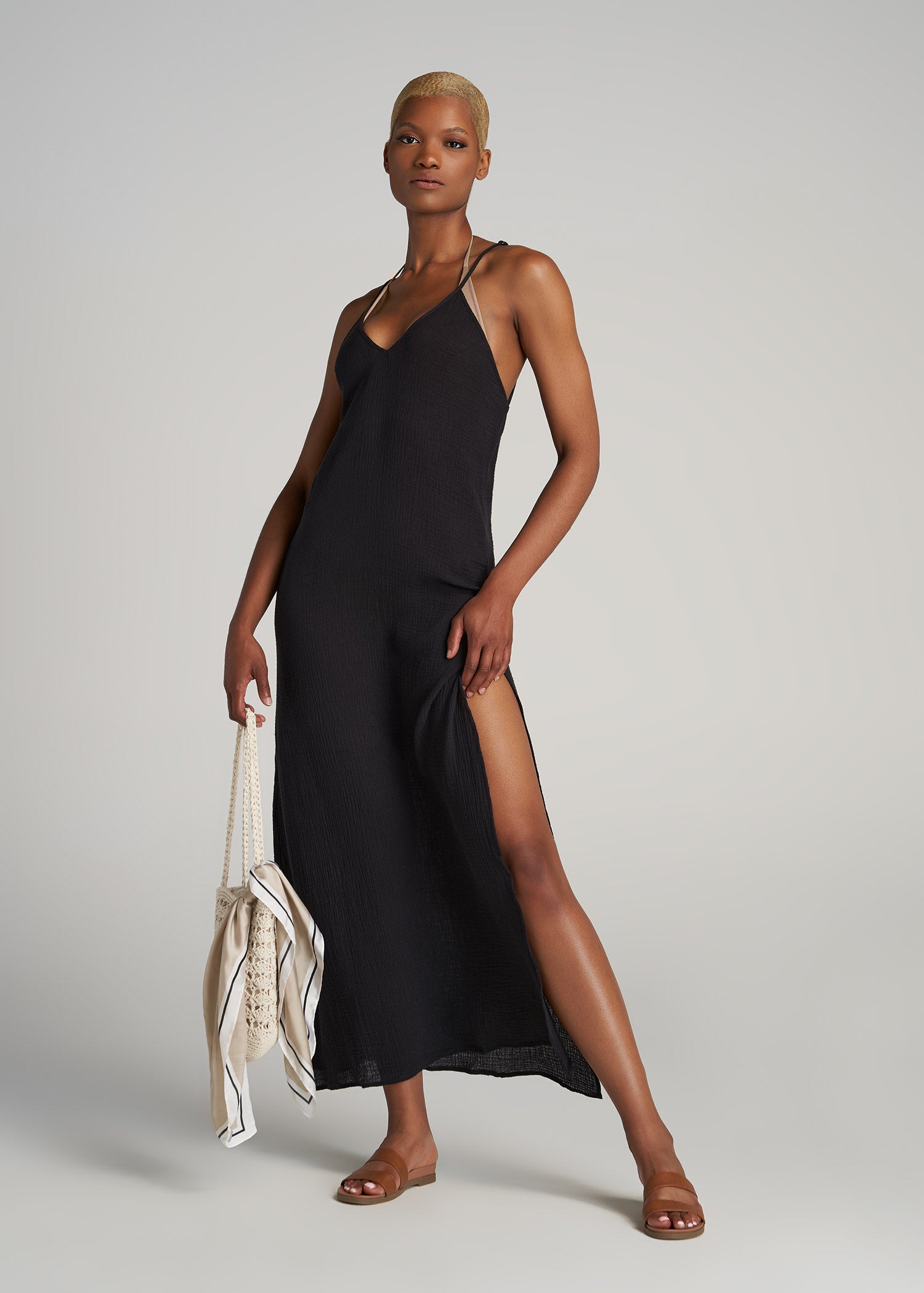 A tall woman wearing a cover-up gauze maxi dress in the color black.
