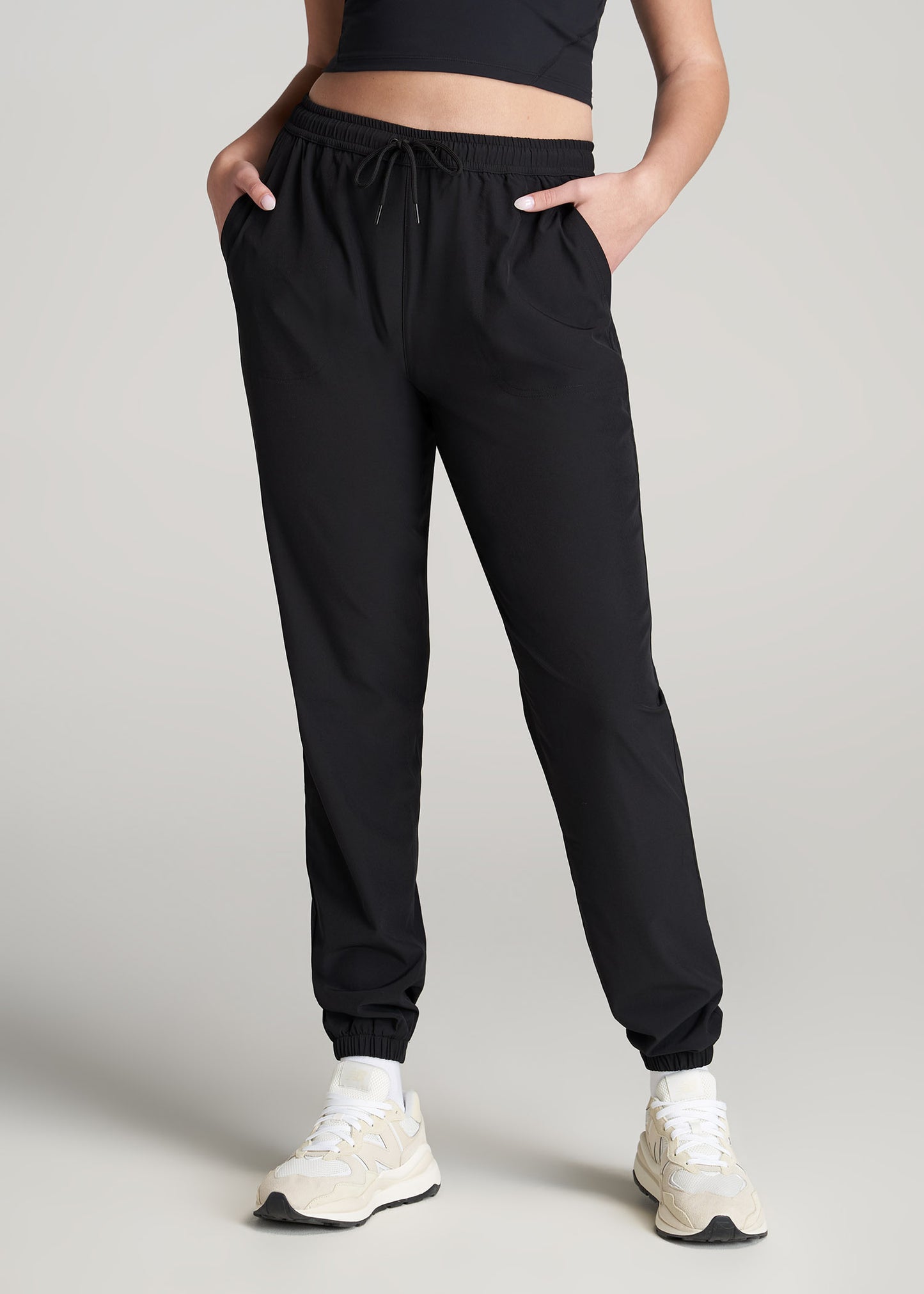 A tall woman wearing American Tall's Hybrid Joggers in the color Black.