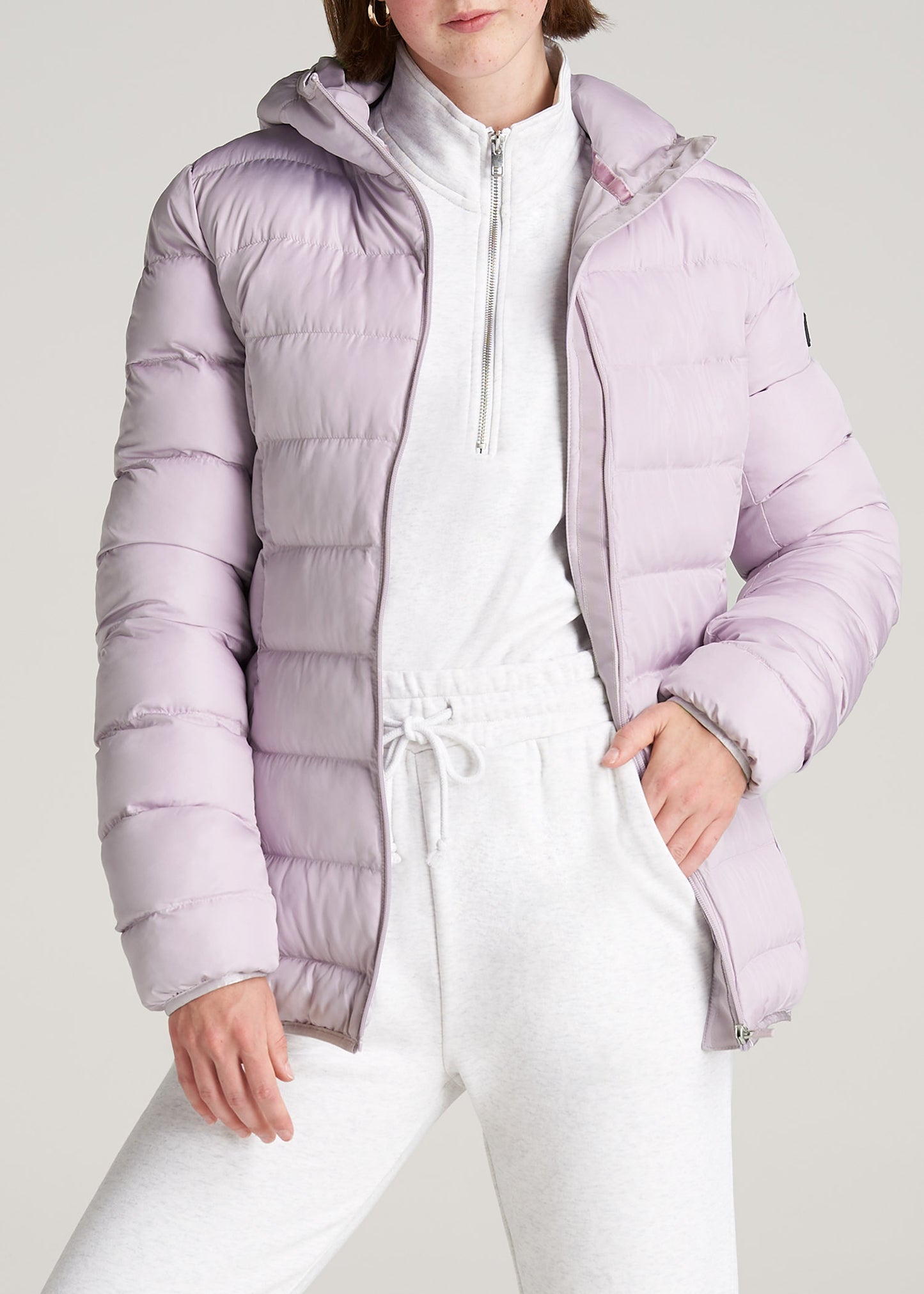 A tall woman wearing American Tall's Women's Tall Hooded Puffer Jacket in Lavender Fog.