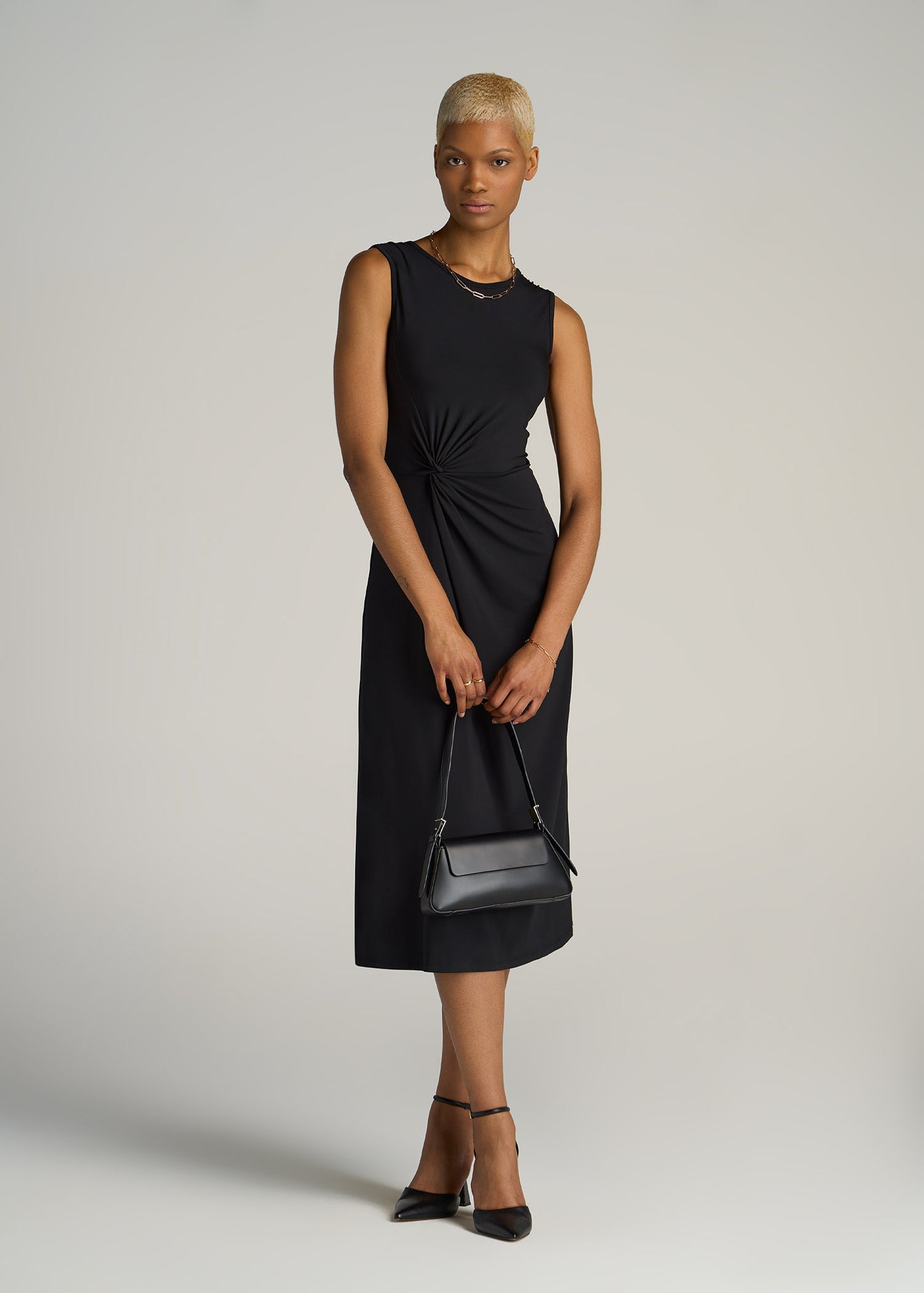 A tall woman wearing American Tall's Sleeveless Knot Front Dress in the color Black.